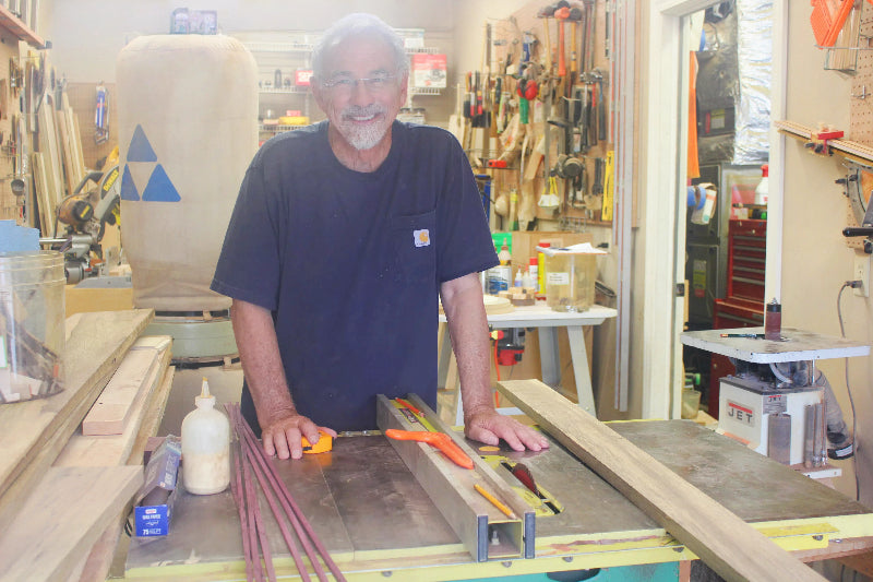 Man working on a table saw in a workshop while smiling. Thom Pabst enjoying making beautiful wood working pieces for those who enjoy well made items.