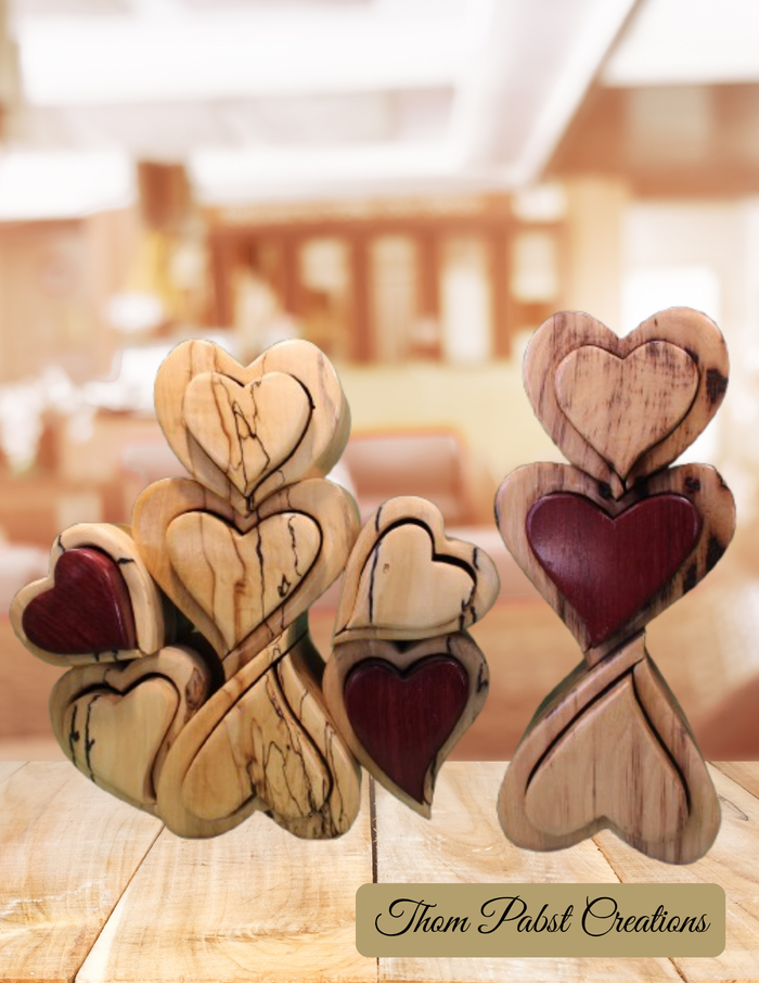 Wooden heart-shaped objects on a white background with 'Thom Pabst Creations' branding.