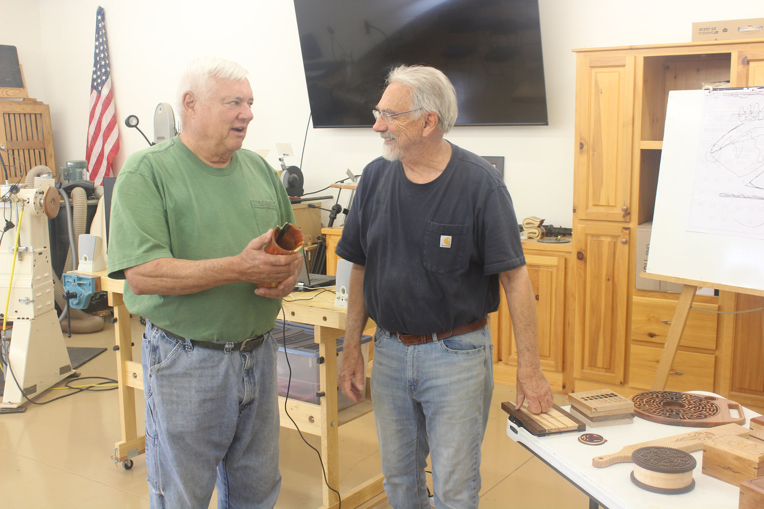 Friends smiling and talking to each other about a good looking wood piece that was made.