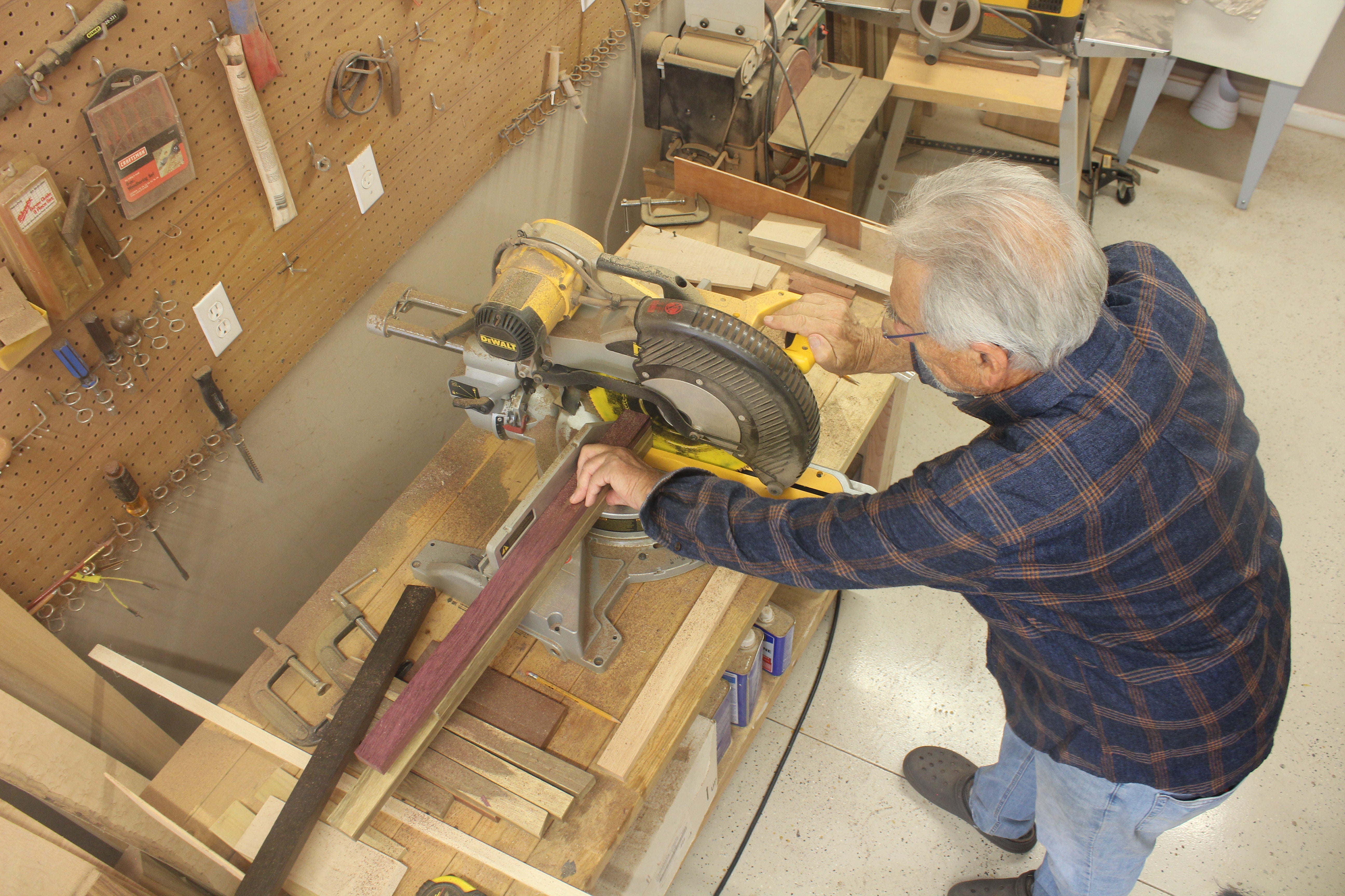 Multiple pieces of wood under a saw to make a wood working piece